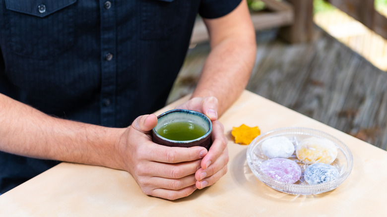 man holding green tea in cup
