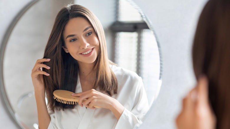 Woman combing hair in mirror