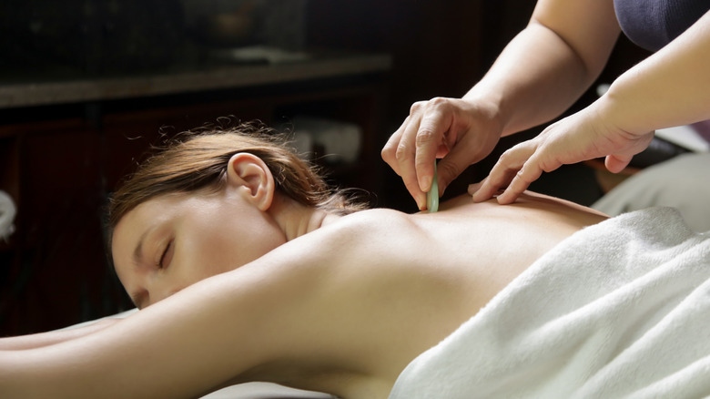 gua sha treatment on a woman's back at a spa 