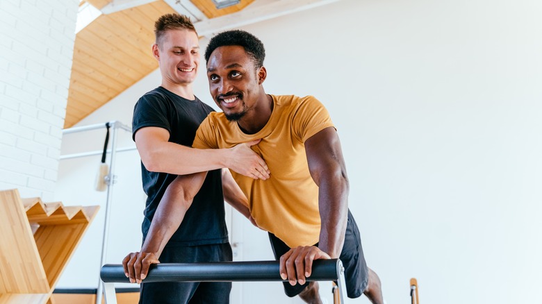 man doing core work assisted by a trainer