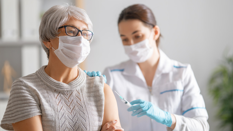 Doctor vaccinating an elderly woman 