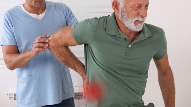 Doctor examining an older male patient with lower kidney pain