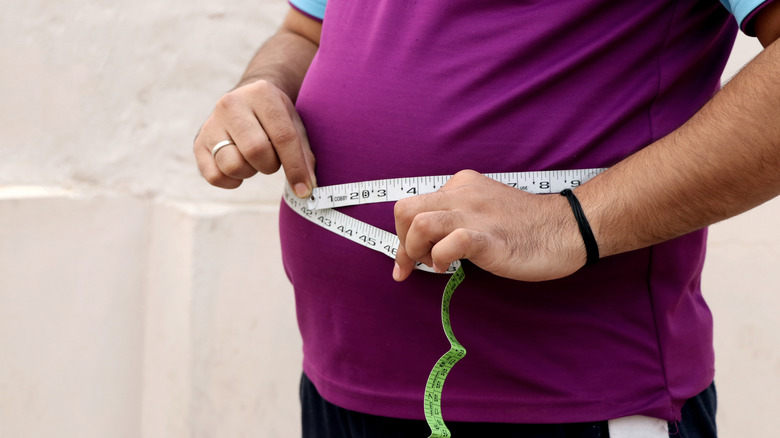 man measuring belly