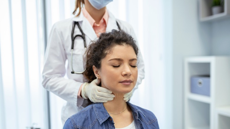 A woman has her thyroid glands check by a doctor