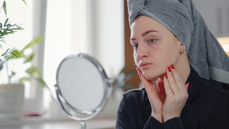 Woman looking at face in mirror