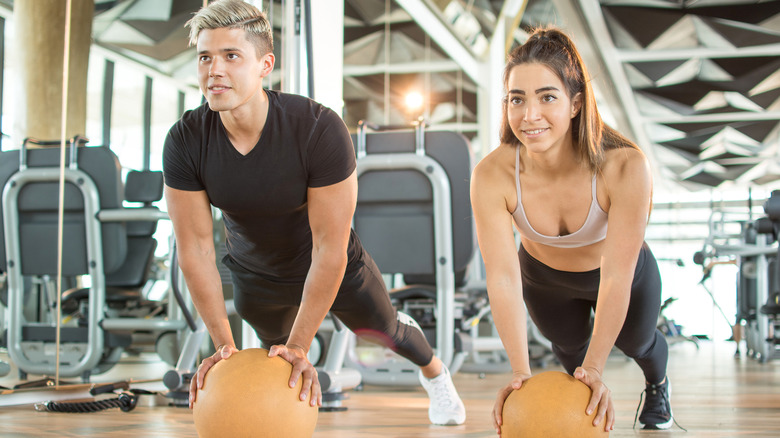 man and a woman doing push-ups on a stability ball