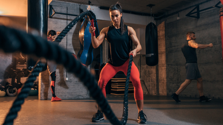 fit woman snapping battle ropes in a circuit