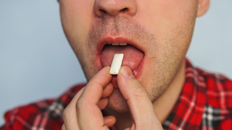 man putting gum in mouth