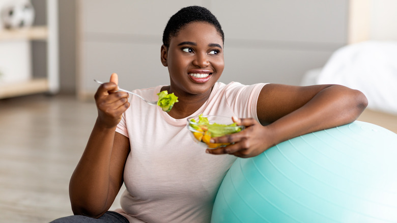 an overweight woman eats a salad and exercises