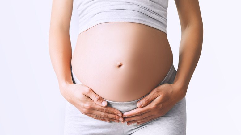 Pair of hands cupping their pregnant belly