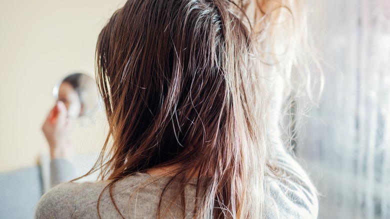 woman looking at her oily hair