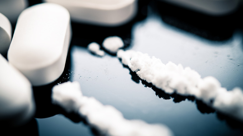 drug tablets and powder on a black surface