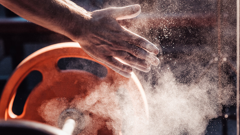 close-up of strong, chalked hand near barbell plate