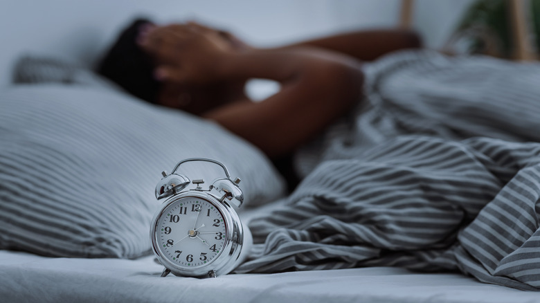 Woman in bed can't sleep in front of alarm clock