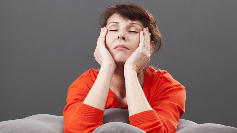 Woman in bed rubbing her temples with eyes closed