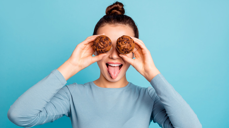 woman holding two chocolate muffins