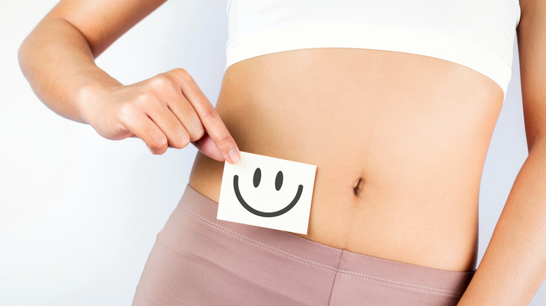 woman holding happy face symbol next to her stomach