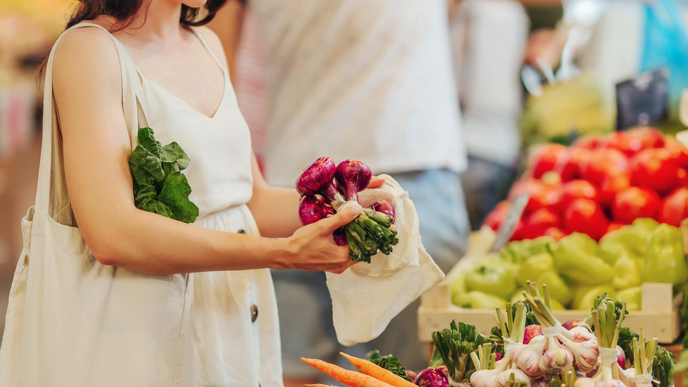 woman placing vegetables in a bag