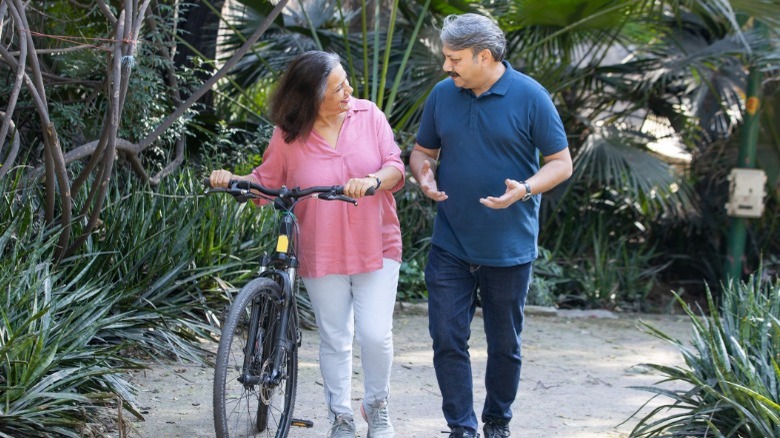 middle-aged couple strolling with bicycle