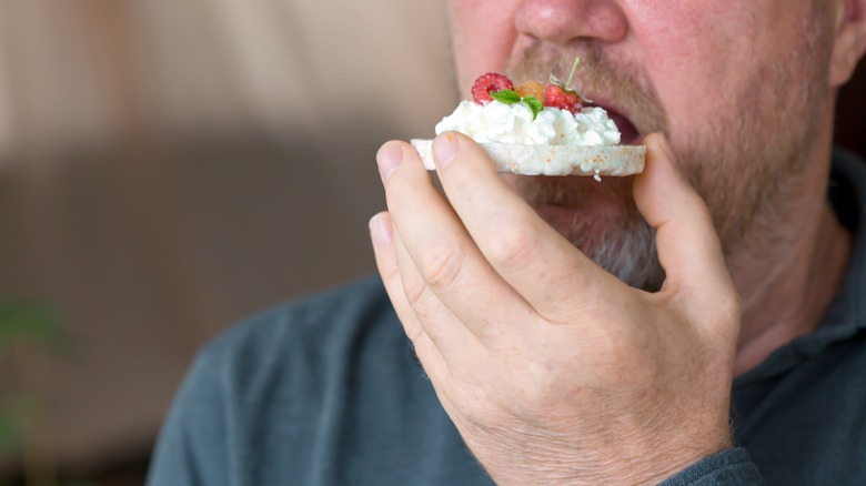 man eating cottage cheese on rice cake