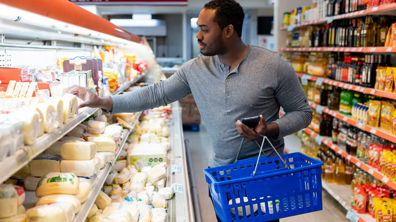 man shopping for cheese in dairy aisle of store