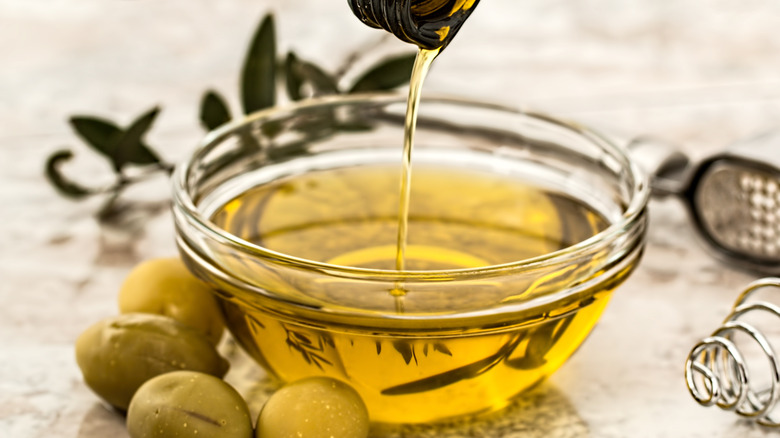 olives and oil being poured into bowl