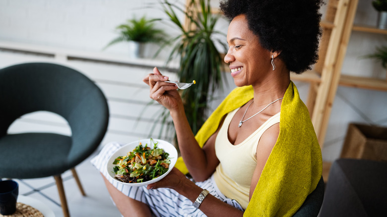 Woman sitting at home eating a salad