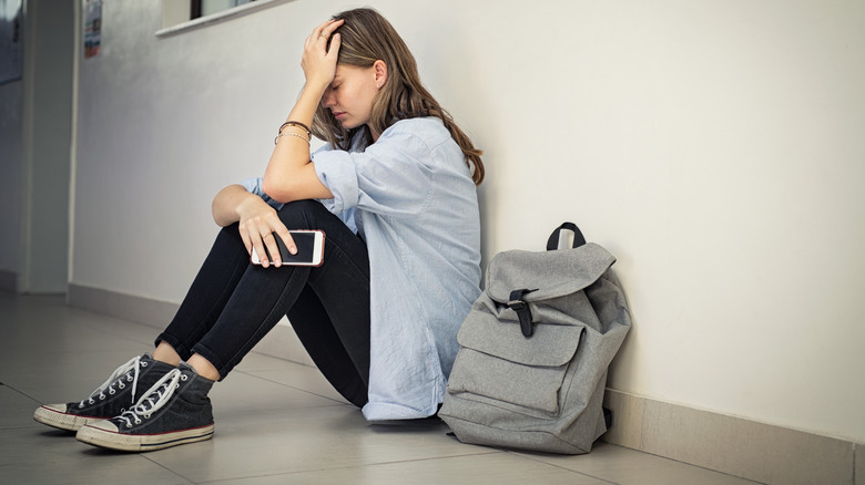 Depressed teen sitting on floor