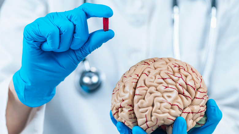 Doctor holding brain model and pill