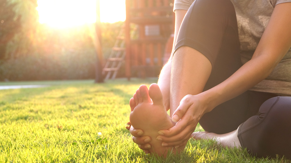 Woman holding foot outside