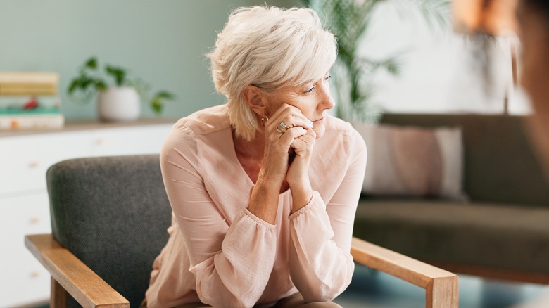 stressed older woman sitting on sofa