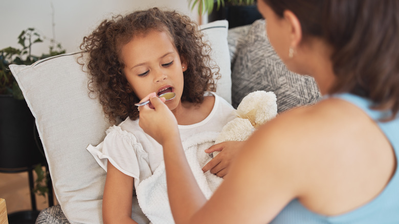 Mother feeding spoonful of broth to child