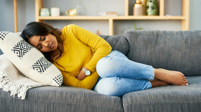 Woman with stomach pain lying on couch