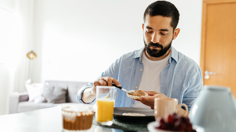 Man spreading peanut butter on rice cake