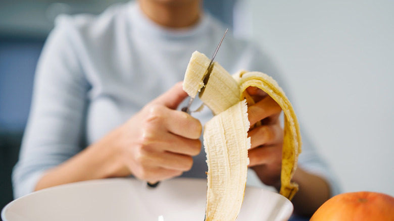 person cutting up banana