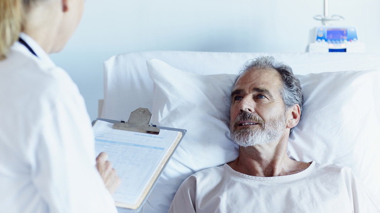 man in hospital bed speaking with medical provider