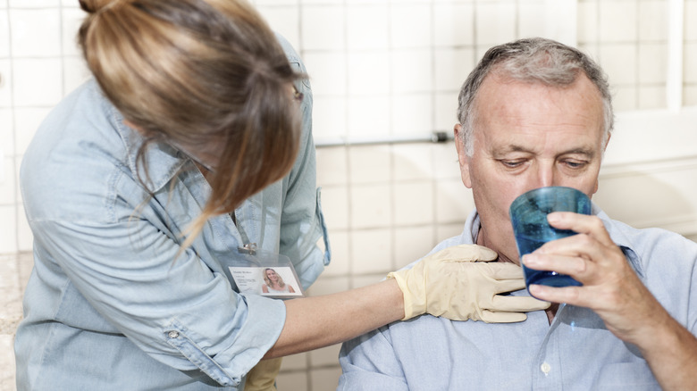 healthcare professional touching patient's throat while he drinks