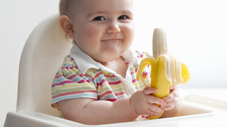 smiling baby holding a banana