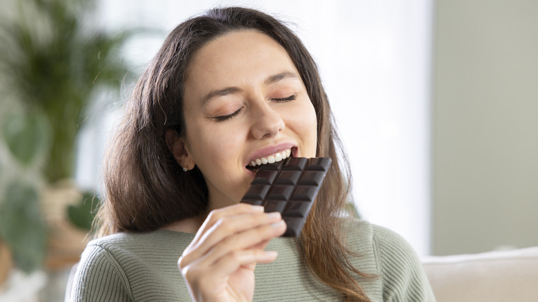 happy woman eating a block of dark chocolate