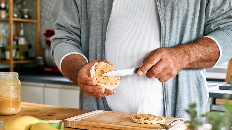 Man spreading peanut butter on rice cake