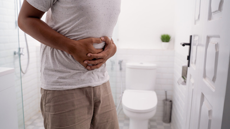 Man in bathroom holding stomach in pain