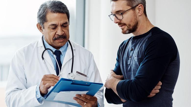 man wearing glasses consulting with male doctor