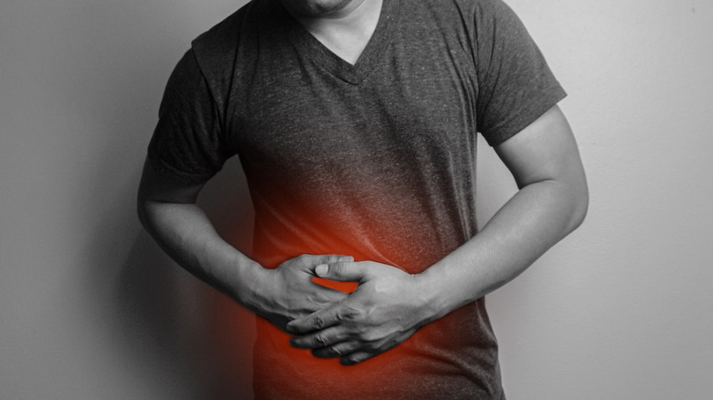 Black and white image of person holding hands over abdomen