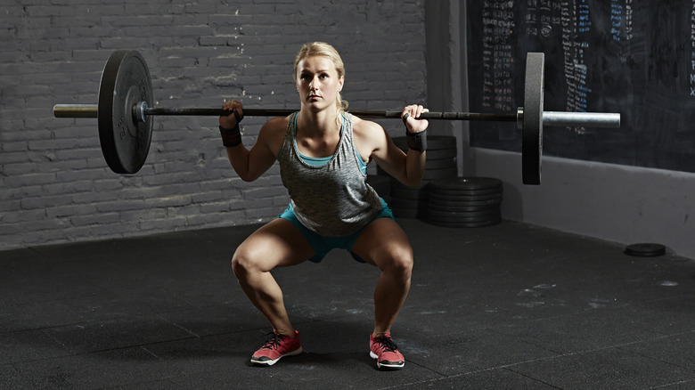 woman doing a barbell squat in a gym