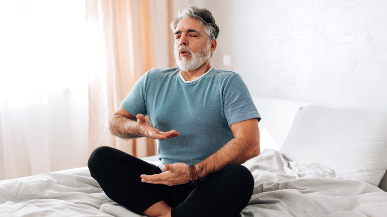 man practicing deep breathing on a bed
