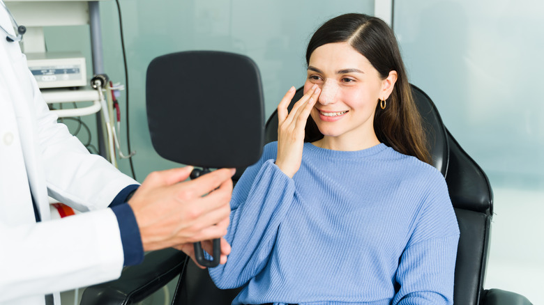 woman touching her nose after nose surgery