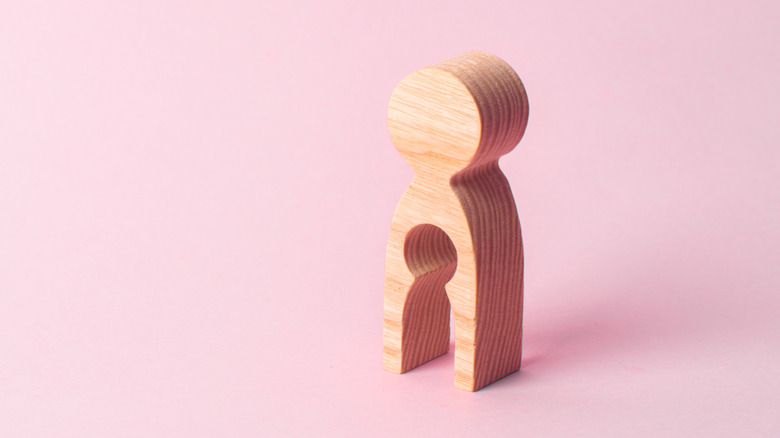 Hollow wooden figure on pink background