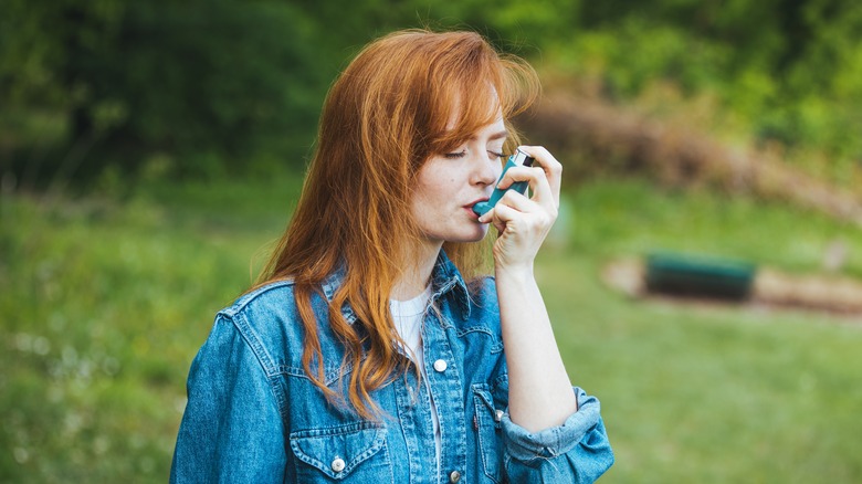 Woman with asthma using inhaler outdoors