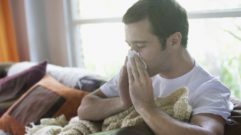 Sick man blowing nose