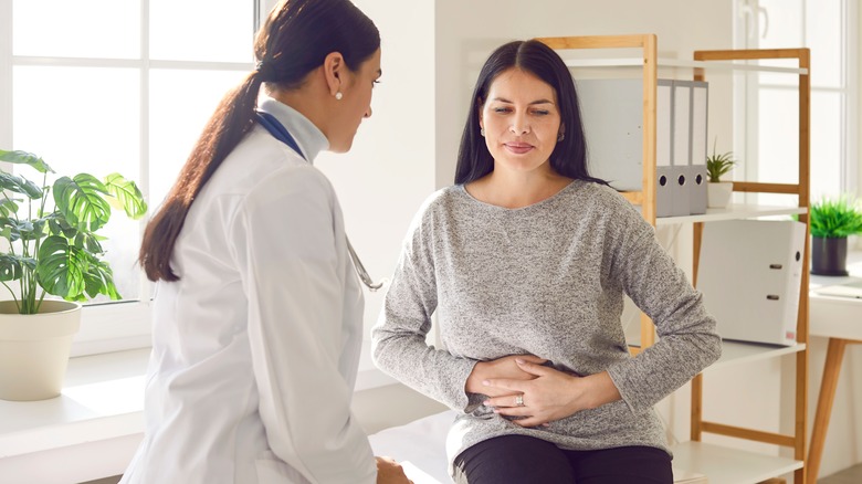 Woman with stomach pain speaking to doctor